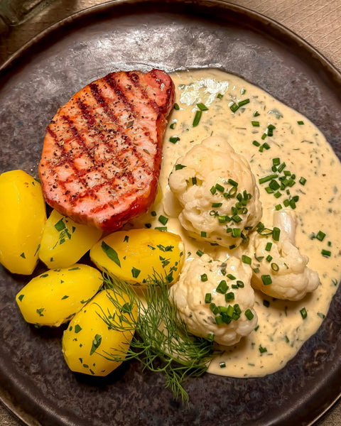 Kasslersteaks vom Rücken mit gebutterten Petersilienkartoffeln und Blumenkohl in Bergkäse-Kräutersoße