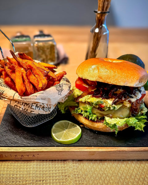 Bagelburger California mit Süßkartoffel-Pommes, Guacamole und BBQ Mayo auf einem Holzbrett