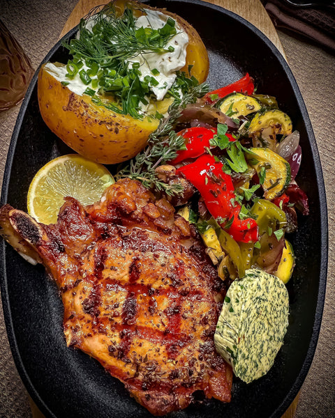 Gegrilltes Duroc-Kotelett mit buntem Grillgemüse, Backkartoffel mit Sour Cream und frischer Kräuterbutter